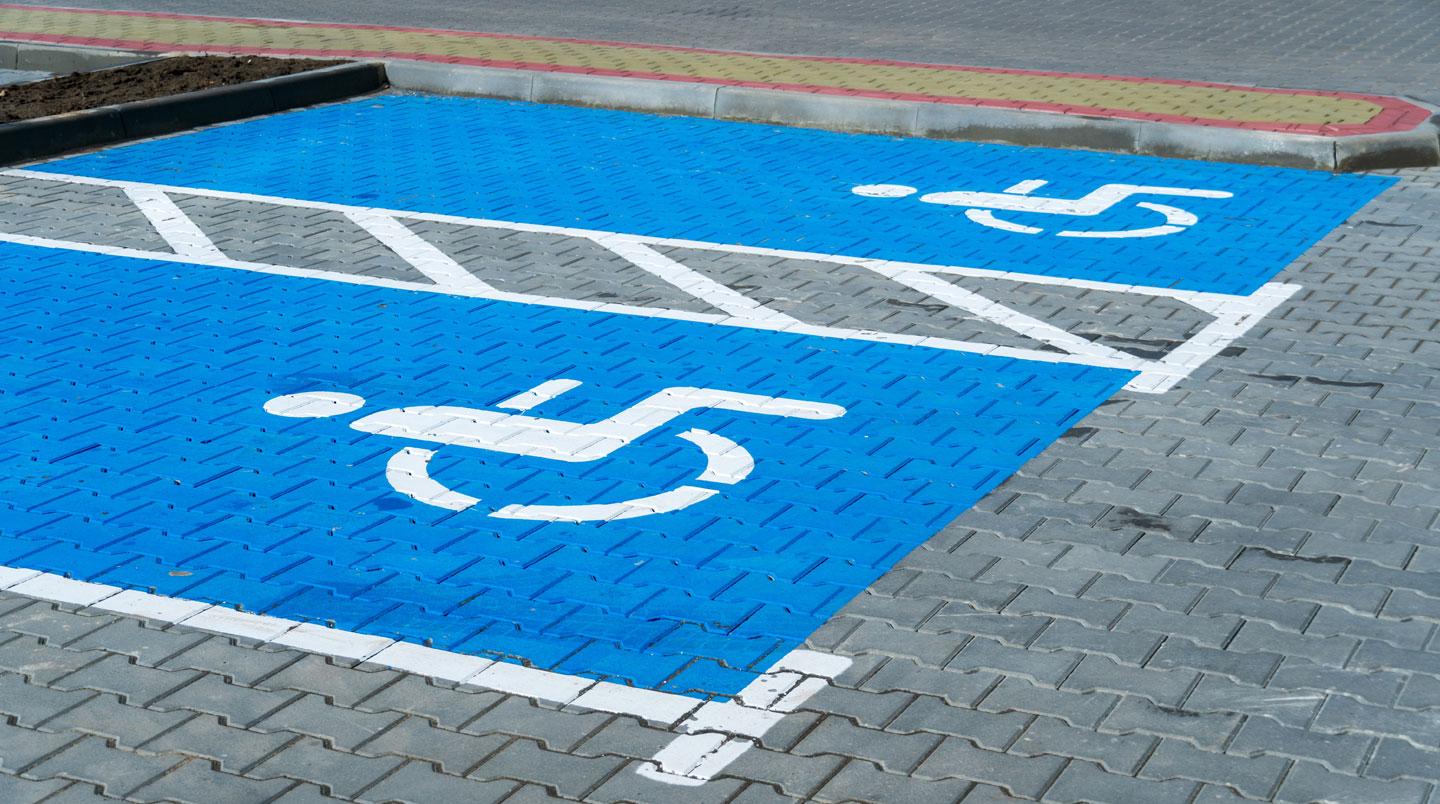 Panneau d'information municipale installé à hauteur accessible avec texte à fort contraste, photographié depuis le niveau d'un fauteuil roulant